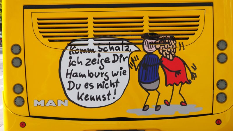 Ein gezeichnetes Bild auf einem Bus. Der Mann sagt der Frau. Komm Schatz, ich zeige Dir Hamburg wie du es nicht kennst.